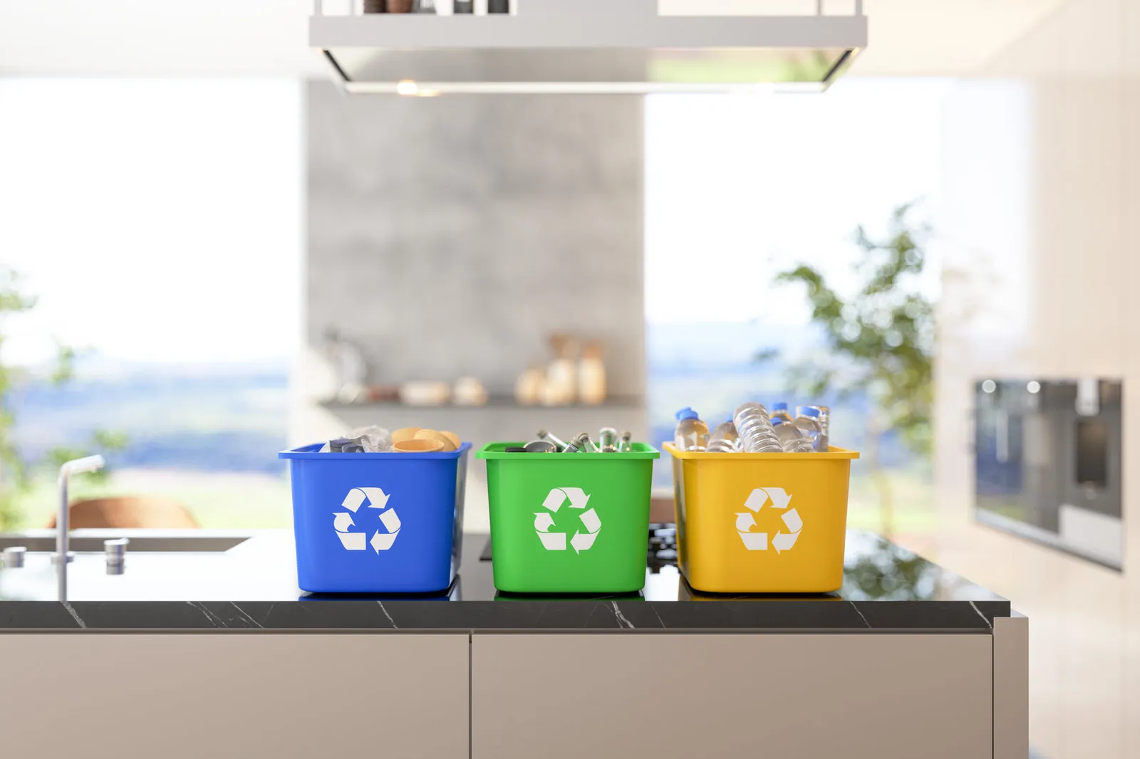 Blue, green and yellow recycling bins filled with cans, bottles and packaging on a kitchen counter