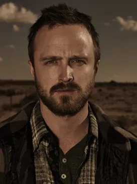 Portrait of Jesse Pinkman from Breaking Bad, a bearded man in a plaid shirt against a desert backdrop.